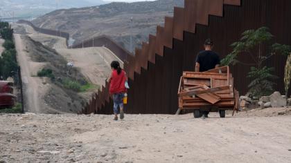 Personas caminan junto a la valla que marca la frontera entre Estados Unidos y México en Tijuana, México.